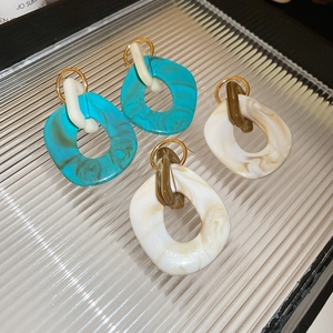 Detail of irregular marble resin earrings in green and cream with golden metal posts