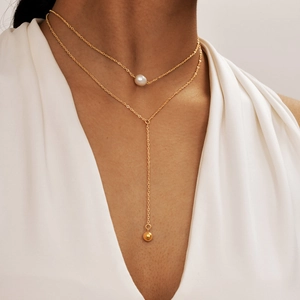 Double-layered gold necklace with white pearl and Y-shaped chain on a model