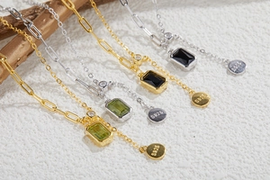 Detail of S925 silver necklaces with rectangle gemstones on textured stone background