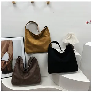 Three large suede tote bags in brown and black displayed on minimalist curved stairs