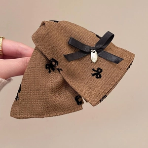 Detail of brown herringbone fabric hair claw clip with black silk bow and metal plaque