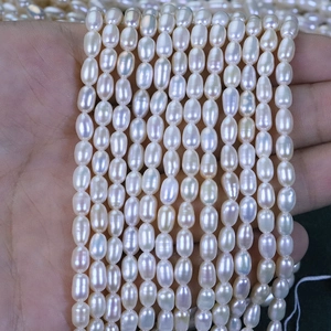 Close-up of 4-4.5mm natural freshwater rice pearls held in hand for jewelry making