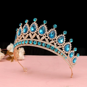 Dettaglio di corona barocca dorata con pietre a goccia blu scuro e accenti floreali