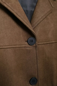 Detailed close-up of brown suede fabric texture with stitching and black button detail