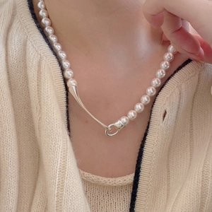 Close-up of minimalist freshwater pearl necklace with unique silver clasp on model