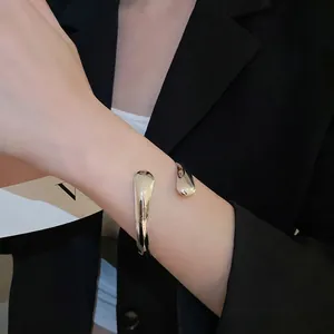 Minimalist silver metal open cuff bracelet featuring asymmetrical waterdrop design on wrist