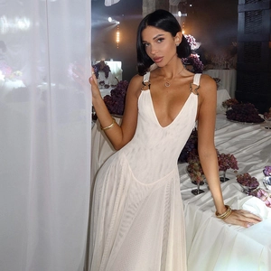 Detail of elegant white deep V-neck mesh evening dress with metal buckle straps in a banquet hall