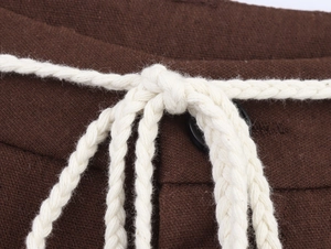 Detail of white braided rope belt on brown cotton linen trousers with fabric texture