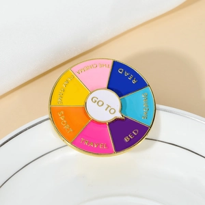 Gros plan d'une broche marguerite dorée en émail avec une roue de décision colorée