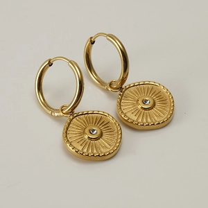 Détail de boucles d'oreilles en acier doré 18K avec pendentif soleil et cristal blanc central