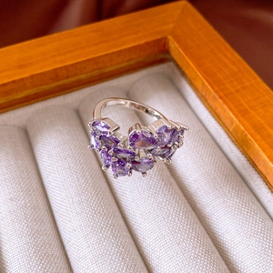 Macro shot of silver ring featuring marquise purple zircon flower cluster on beige lining