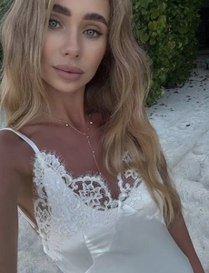 Detalle de vestido de satén blanco con encaje y fino collar de cuentas doradas