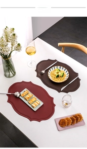 Detailed view of scalloped edge faux leather placemats in deep red and brown colors