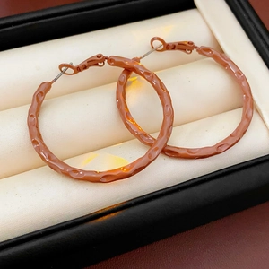 Macro view of brown clay hoop earrings with hammered texture in a jewelry gift box