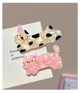 Detail of two cute acrylic cat hair clips with pearl finish and party hats on card