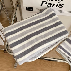 Detail of grey and white striped plush bath towel folded neatly on a glass shelf