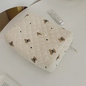 Detail of quilted corduroy bear embroidery pouch with branded label and ribbon zipper pull