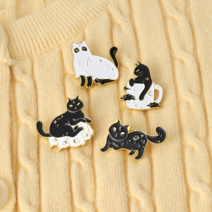 Detail of four enamel cat pins with moon and star patterns on a knitted sweater