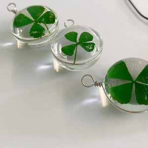 Detail of three transparent resin pendants with real lucky four-leaf clover specimens