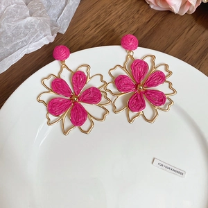 Detail von böhmischen Raffia-Blumenohrringen in Gold und Magenta für den Urlaub