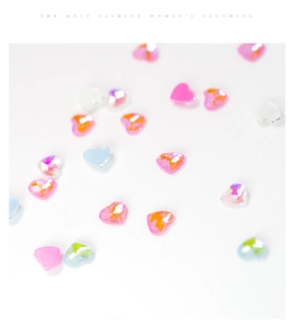 Macro shot of colorful iridescent heart-shaped nail art rhinestones on a white surface