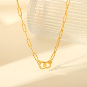 Detail of gold paperclip chain necklace featuring a unique handcuff charm pendant