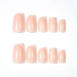 Detailed view of glossy white French tip press-on nails with heart patterns and square shape