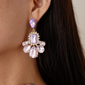 Close-up of vintage gold earrings with purple teardrop crystals worn by a model