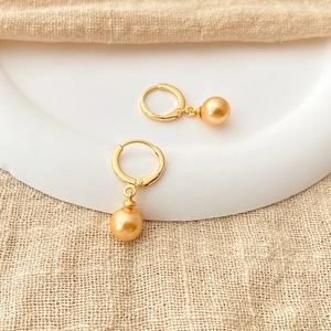 Elegant 18K gold plated hoop earrings featuring colorful shell pearls on a white plate