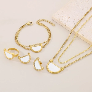 Detail of gold jewelry set with white acrylic accents featuring necklace, earrings and ring