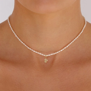 Close-up of a pearl necklace featuring a golden snake pendant on a model neck