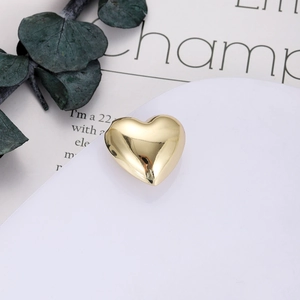 Dettaglio del ciondolo a cuore in oro lucido su espositore bianco con foglie decorative