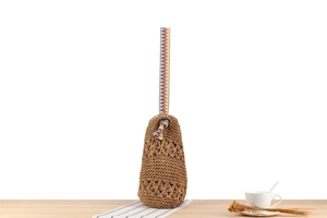 Detail of bohemian handwoven paper rope bag with colorful geometric strap and floral pattern