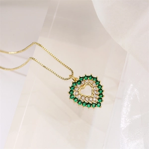 Détail du pendentif cœur serti de zircons verts et blancs sur chaîne dorée