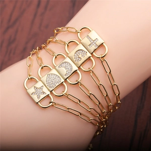 Détail d'un bracelet en chaîne dorée avec breloques lune, étoile et cœur en zircone au poignet
