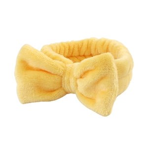 Detail of soft yellow coral fleece headband with bow for skincare and makeup routines