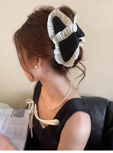 Detail shot of a Korean-style pleated black and white bow hair clip worn by a model
