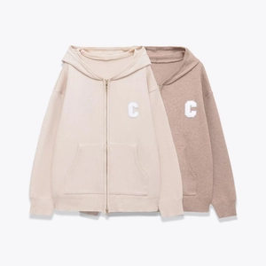 Detail of zip-up knit cardigans in beige and brown with letter C patch on clean background