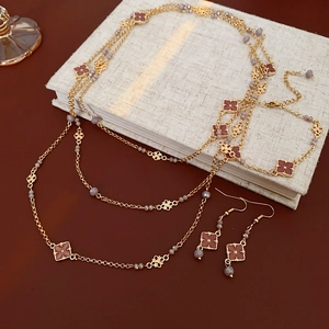 Detailed close-up of vintage gold necklace and clover earrings with red enamel inlay