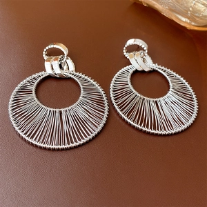 Dettaglio di orecchini a cerchio in mesh argento con intricato intreccio di fili metallici