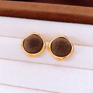 Close-up of vintage square earrings with brown flocking and gold metal frame on velvet