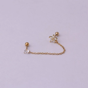 Detail of gold-plated double piercing earring featuring a zircon flower and dainty chain
