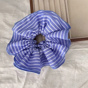 Blue and white striped scrunchie for low bun hairstyles on white linen background