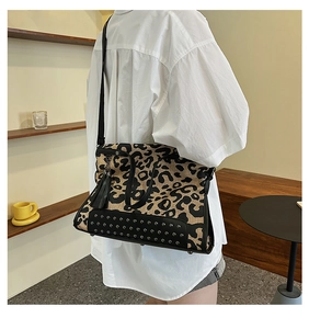 Leopard print tote bag with rivet details and tassel shown being worn by a model