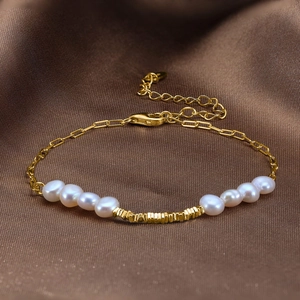 Detail of freshwater pearls and golden disk charms on a delicate sterling silver bracelet