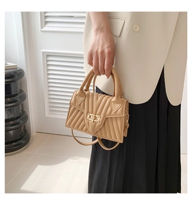 Detail of khaki quilted crossbody bag featuring a golden twist lock and V-stitch pattern
