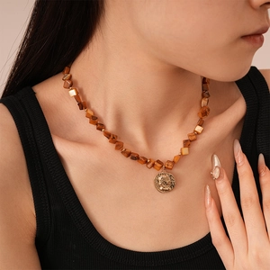 Detail of vintage coin pendant necklace with brown tiger eye beads on model