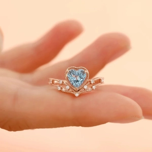 Rose gold ring with heart-shaped light blue topaz stone and sparkling diamond accents