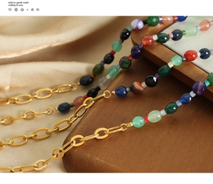 Détail d'un collier de perles d'agate colorées avec maillons dorés et texture riche