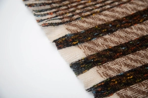 Macro detail of striped knit scarf fabric with textured fringes and beige brown yarns